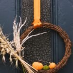 Fall door decor wreath with warm autumn colors hanging on a front door