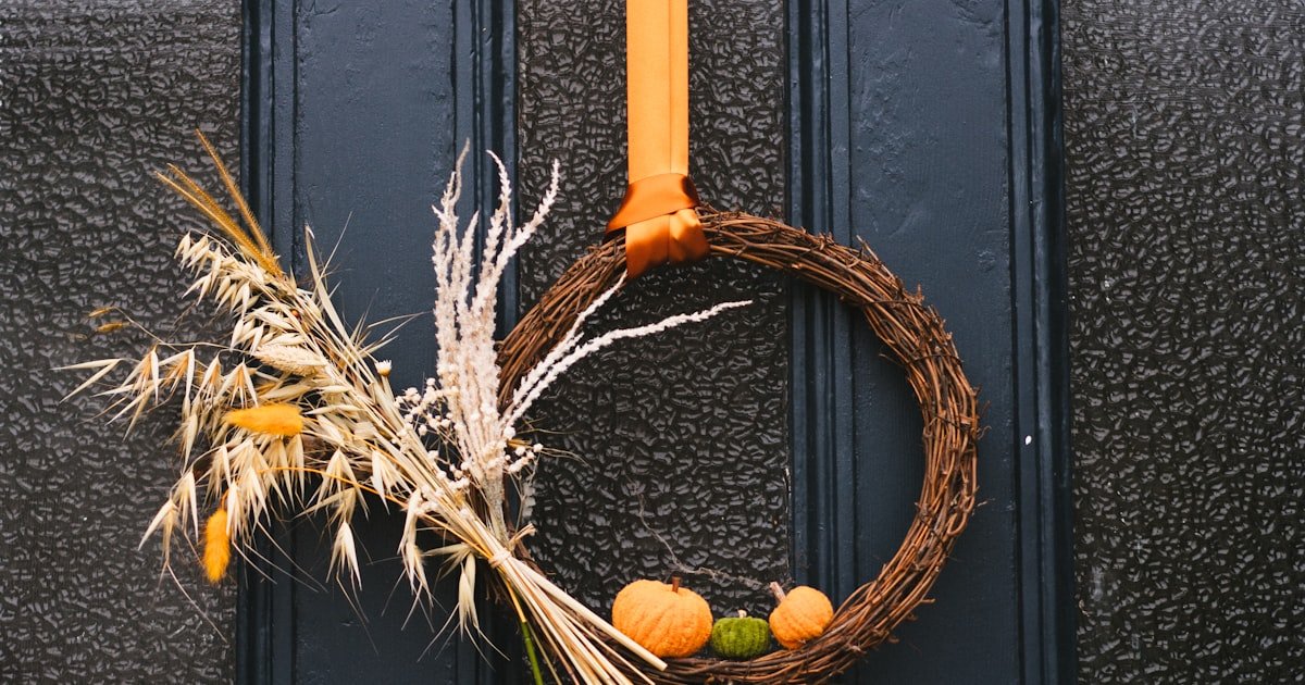 Fall door decor wreath with warm autumn colors hanging on a front door