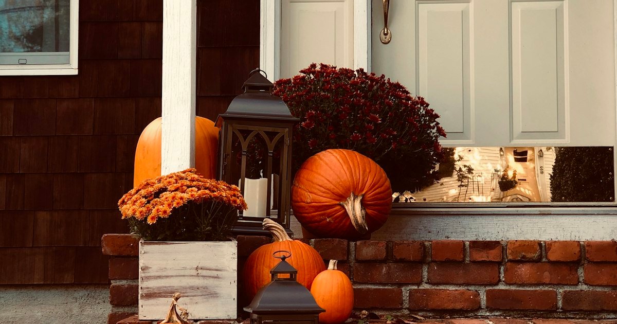 Fall porch decor with pumpkins arranged on outdoor steps in a triangle pattern