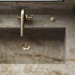 Gold bathroom decor with a brushed gold faucet and mirror