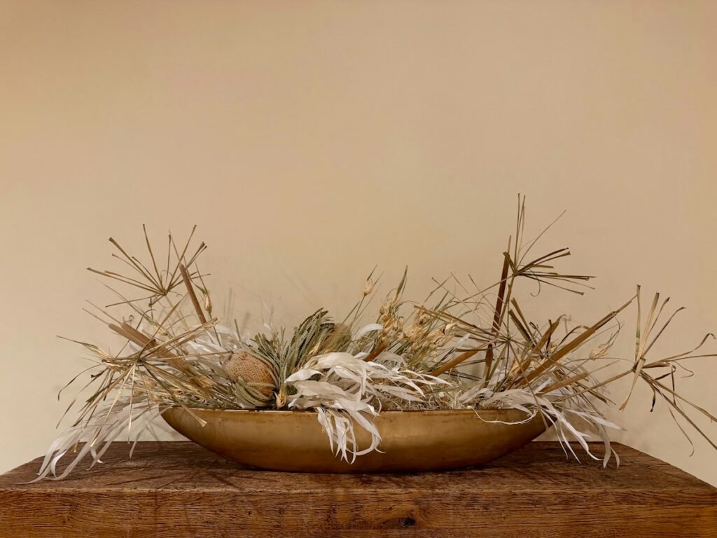 Golden bowl filled with dried grasses and flowers