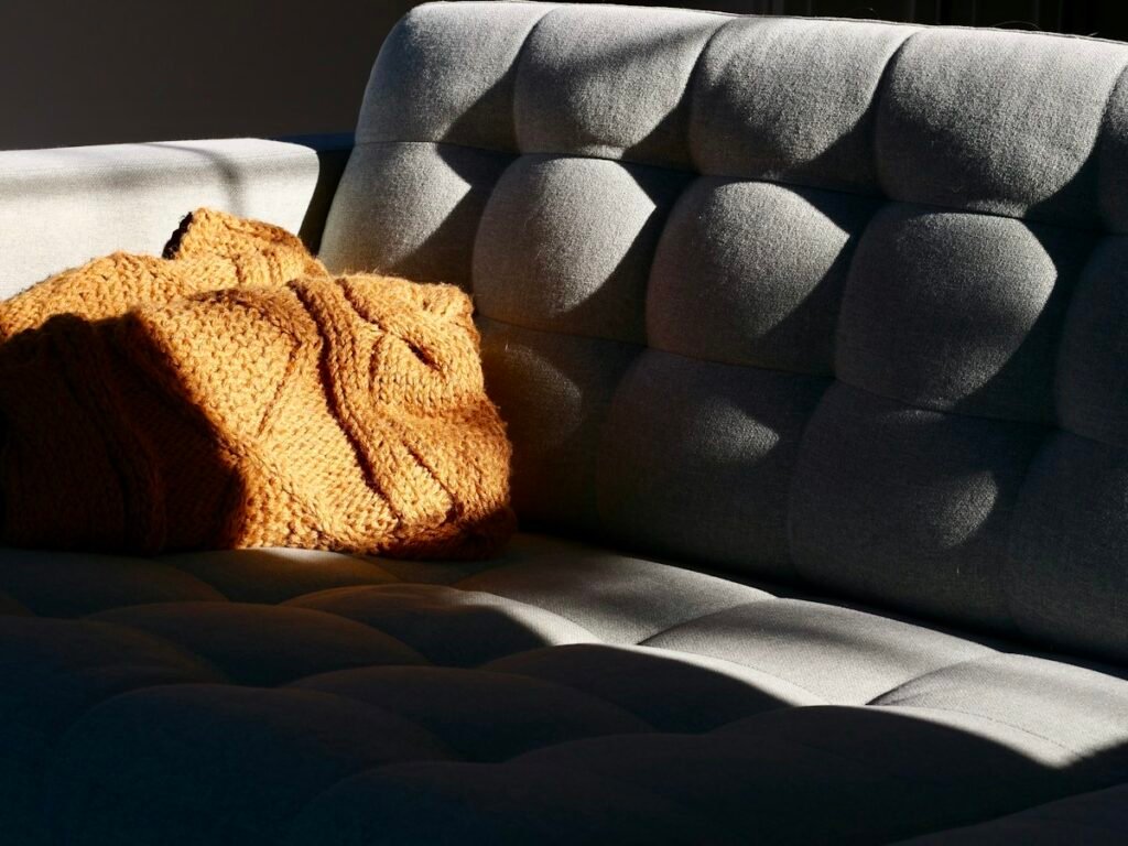 Mustard knitted blanket on a gray tufted sofa