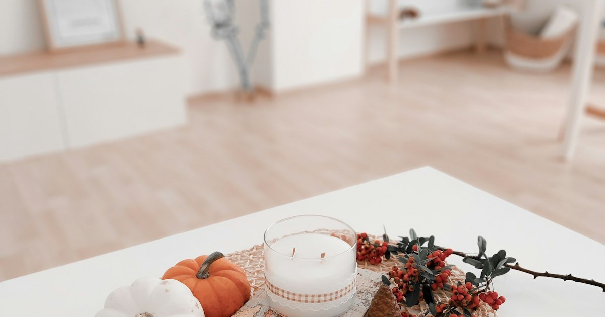 Pumpkins and a candle on a white dining table