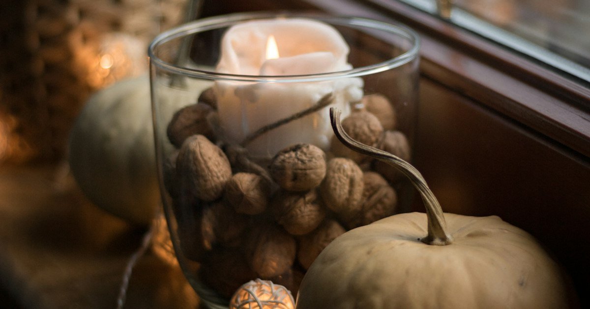 Candle and small pumpkins on a window sill