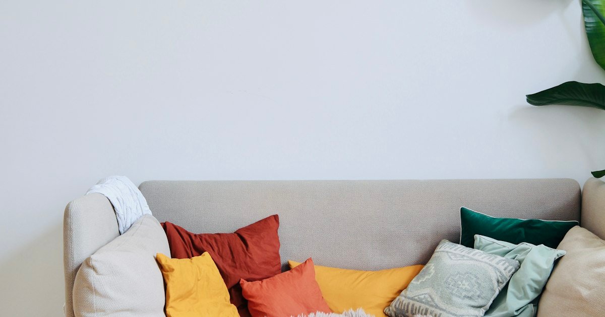 Orange boho decorative pillows layered on a white couch