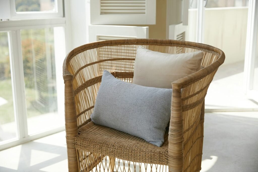 Brown wicker armchair with a gray throw pillow