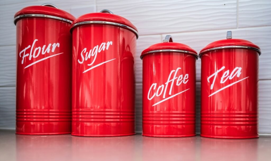 Four red retro canisters labeled flour, sugar, coffee and tea