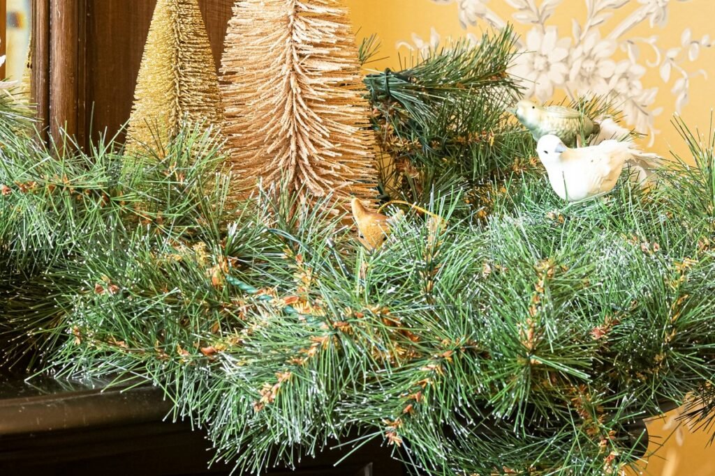 A fireplace mantel decorated with pinecones and evergreen branches, the look the $25 dollar tree diy christmas decorations plan copies