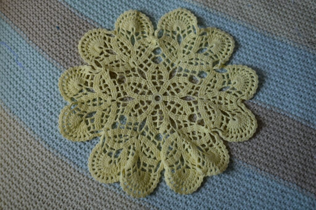 Cream crochet doily for diy doily wall decor laid flat on a striped blanket