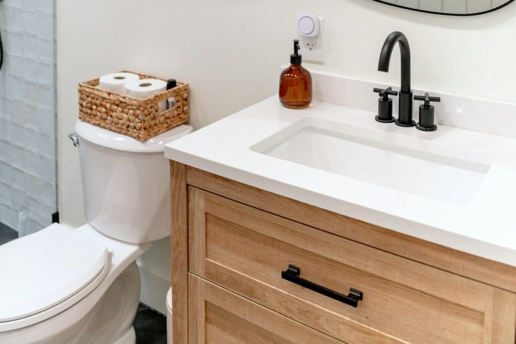 Small bathroom with a light wood vanity, a white sink, a black faucet and an irregular mirror, bathroom decor ideas on a tight budget for renters