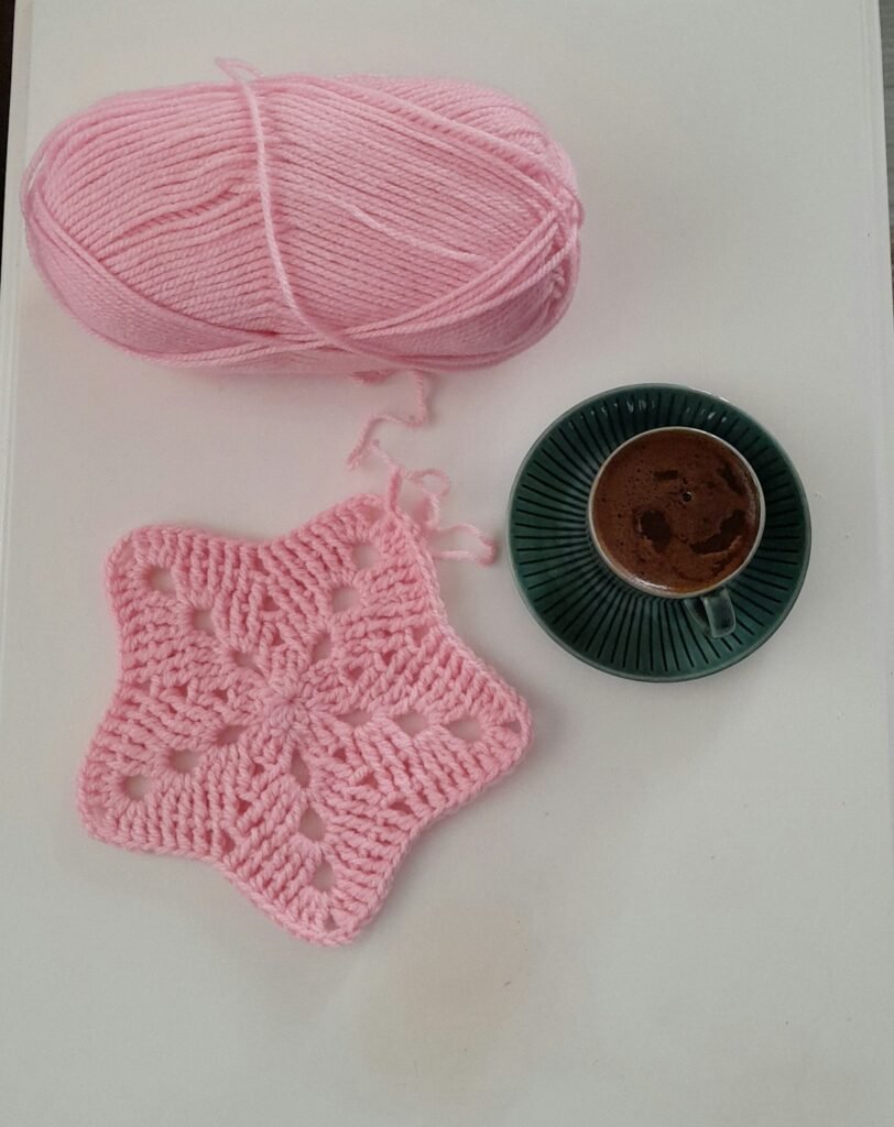 Star-shaped crochet doily beside pink yarn, ready to stiffen for a wall hoop