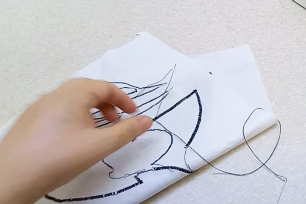 The back of a fabric panel showing dark lines of stitching that outline each shape