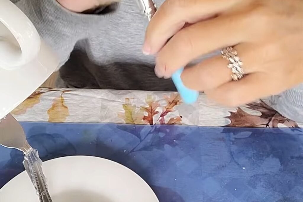 A hand holding a blue silicone finger protector over a table