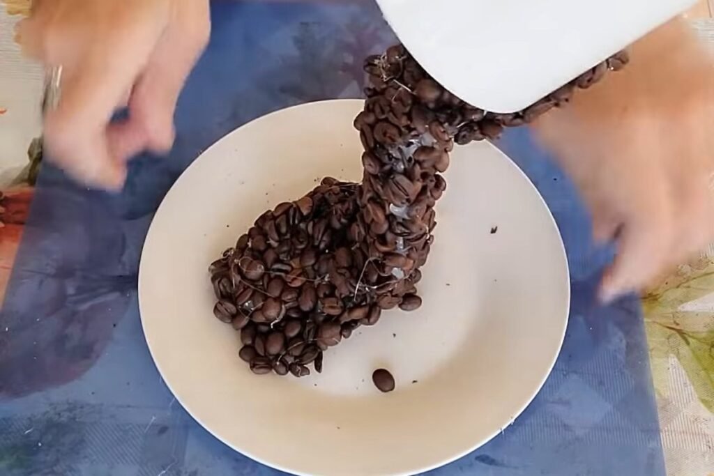 A coffee bean stream running from a white cup down to a pile on a white saucer
