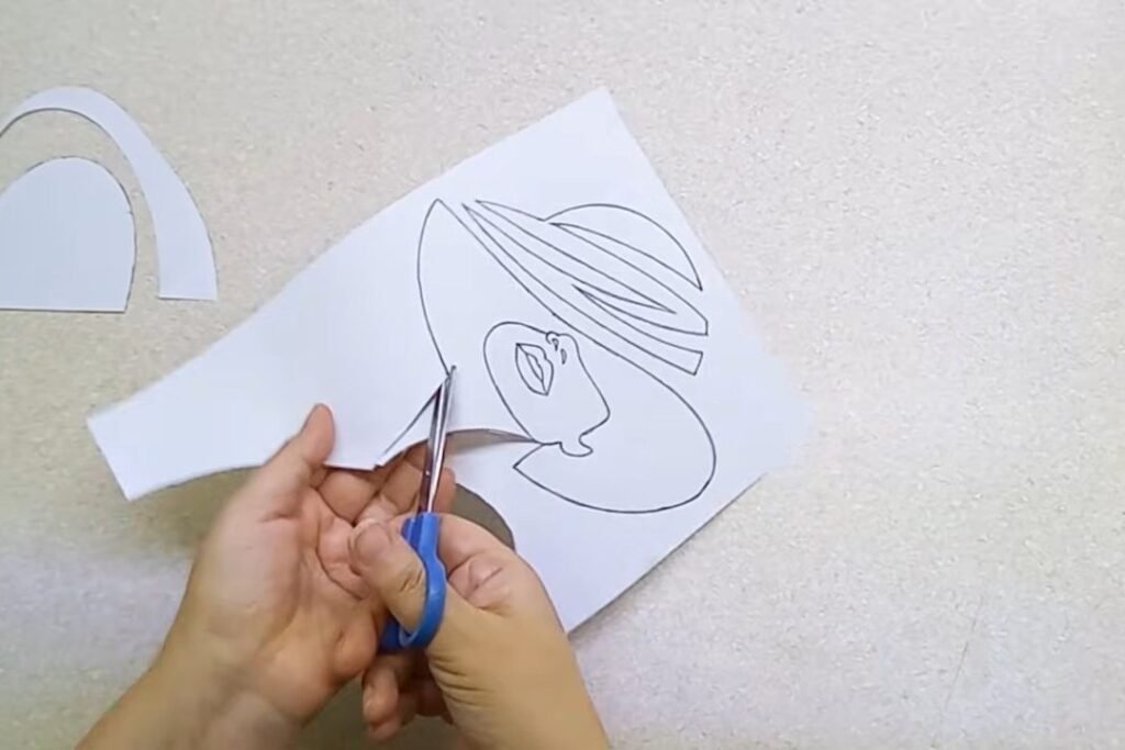 Blue-handled scissors cutting a printed outline into separate paper shapes