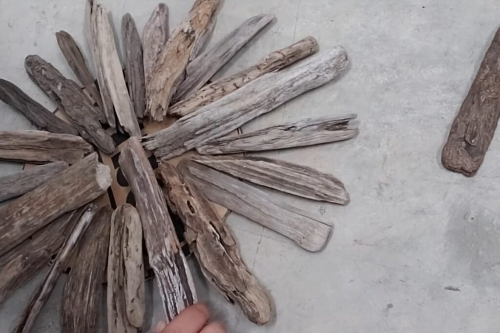 A full ring of driftwood pieces laid loosely around a cross before gluing
