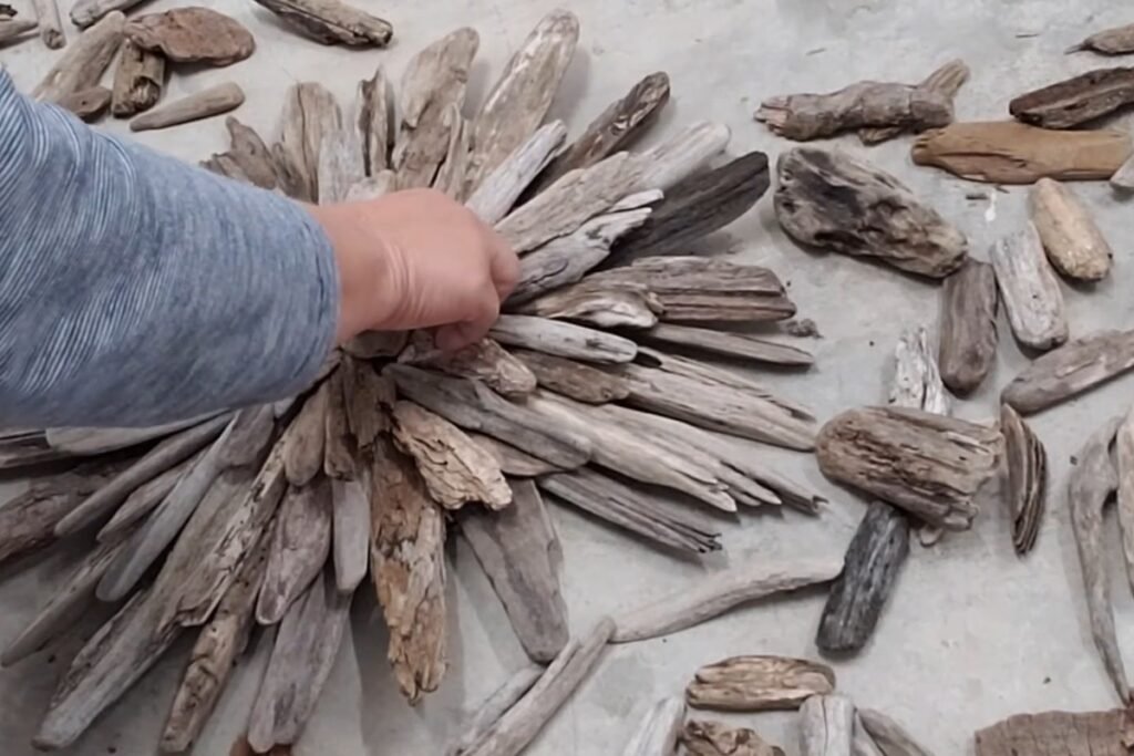 Hand pressing a flat driftwood piece into the centre of a starburst