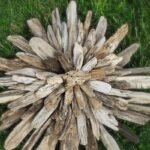 Finished driftwood starburst coastal wall decor piece lying on green grass