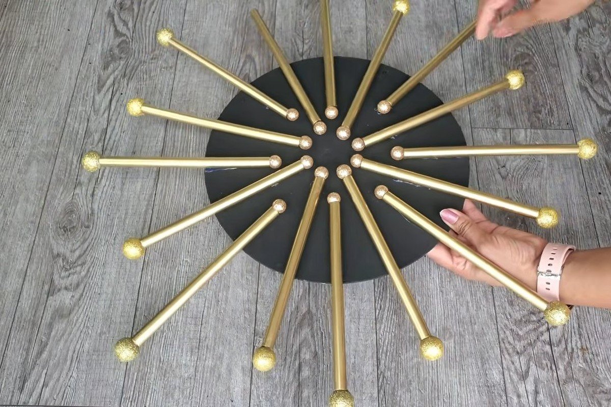 Dollar Tree wall decor finished: a black wooden circle with gold straw rays and gold glitter balls on every ray