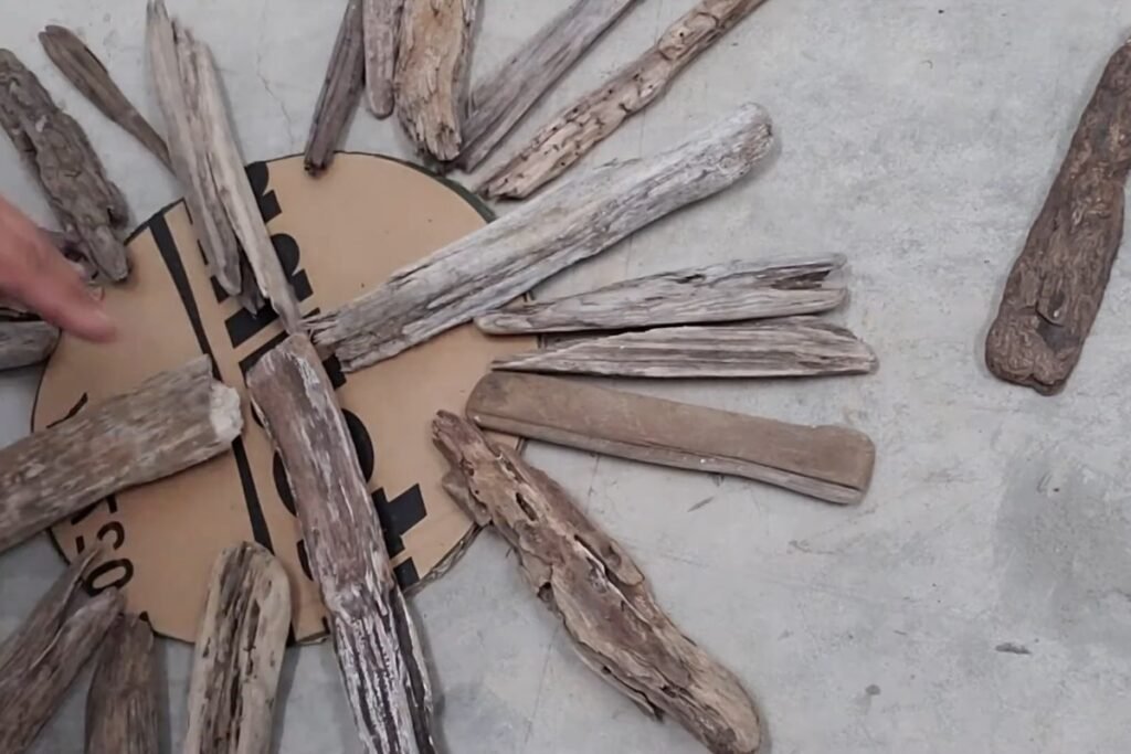 Shorter driftwood pieces being fitted between the main arms on a cardboard base