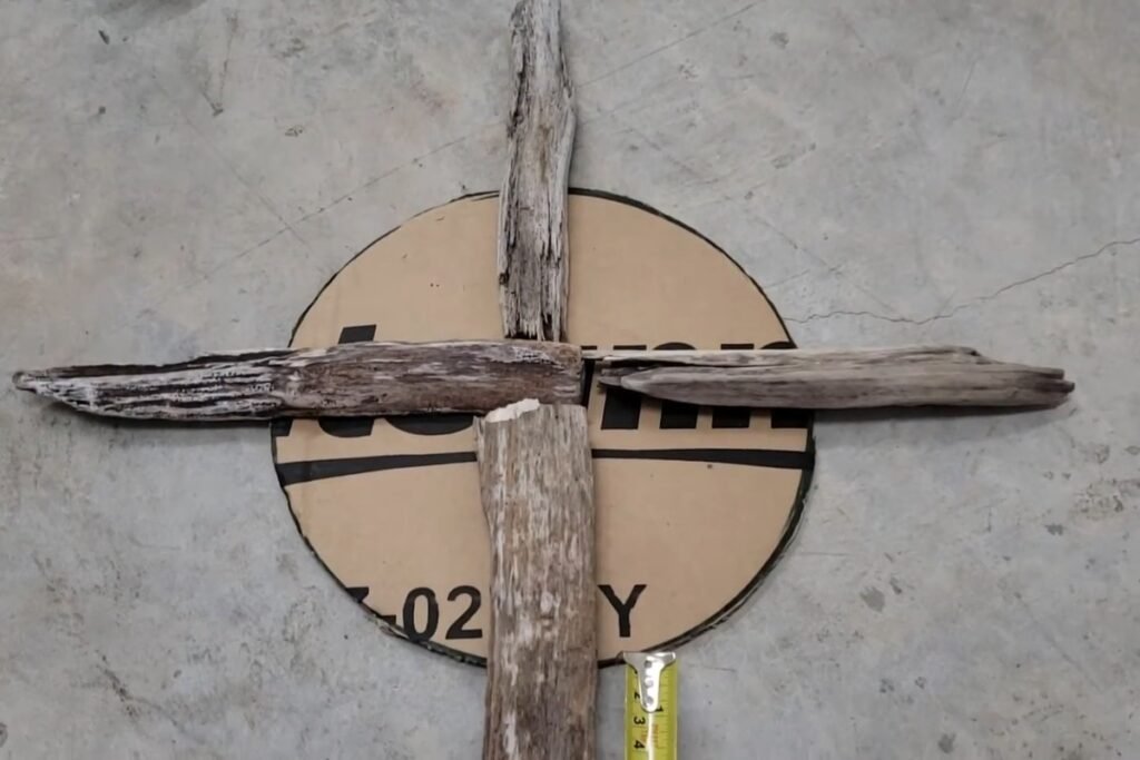 Four long driftwood sticks laid in a cross over a cardboard circle