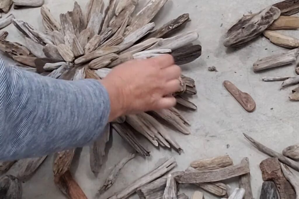 Hand gluing short driftwood pieces in a ring around the centre of a starburst