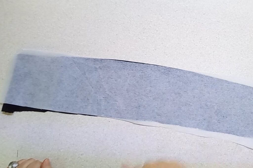 A long strip of black fabric with grey fusible interfacing covering its back