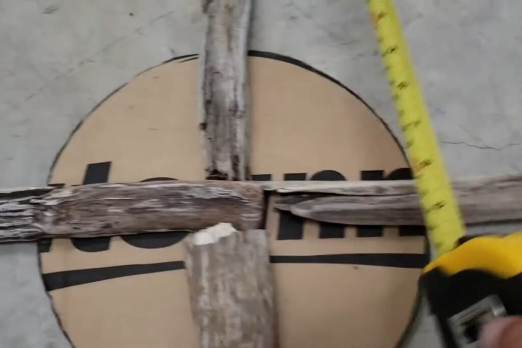 Tape measure checking how far a driftwood arm extends past the cardboard circle