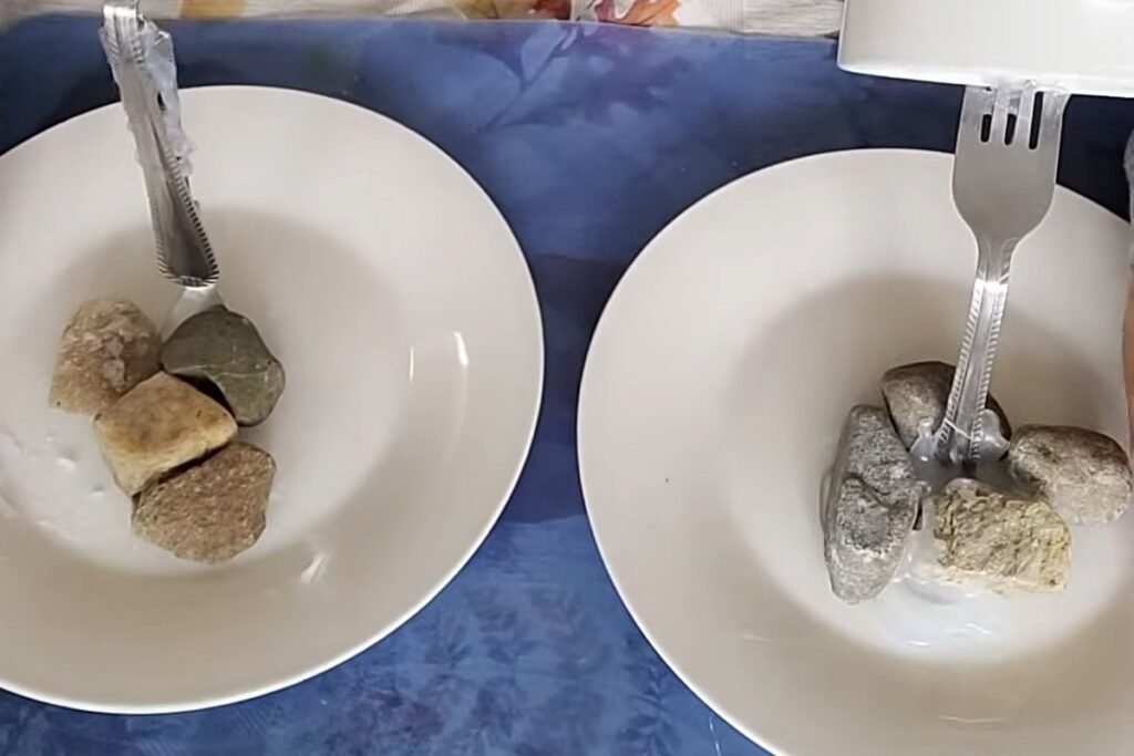 Two white saucers, each with a fork standing in a small pile of pebbles