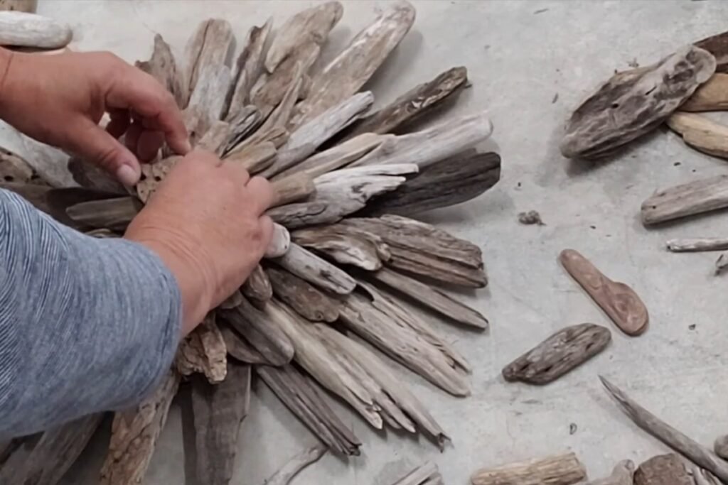 Hands placing a knotted driftwood piece in the middle of a layered starburst