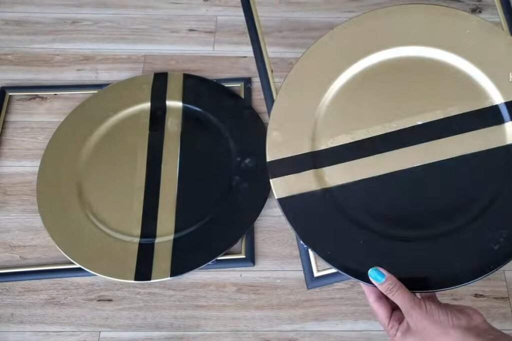 Two gold and black striped plates laid beside two empty picture frames on a wooden floor