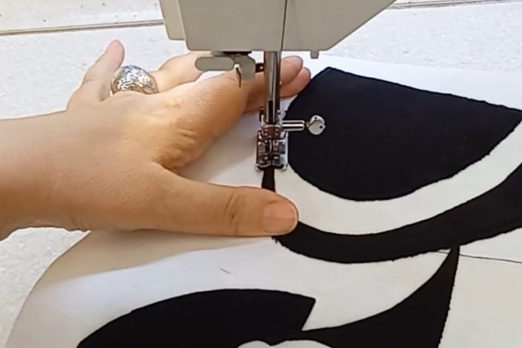 A needle stitching along a smooth curved edge of a black fabric shape