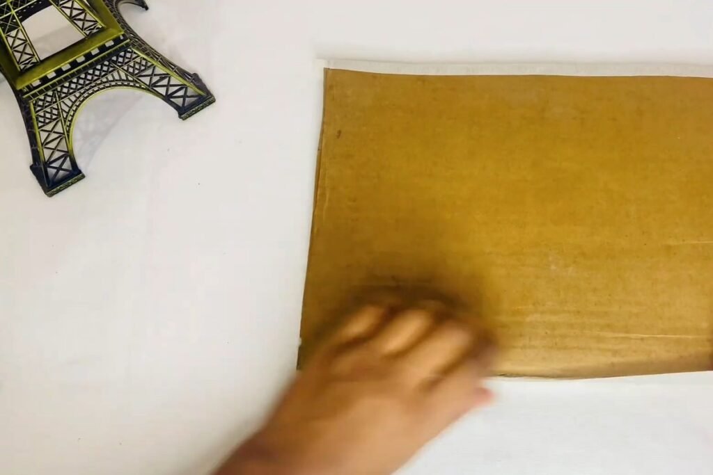 Hand pressing masking tape flat along the edge of a cardboard back sheet