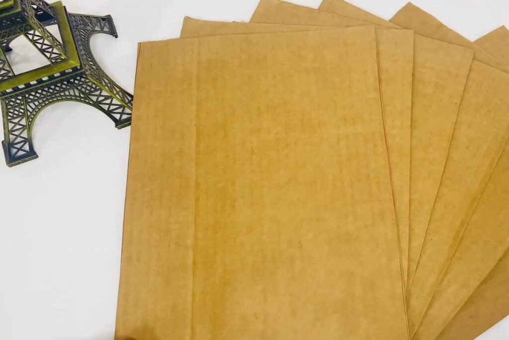 A stack of flat corrugated cardboard sheets fanned out on a white table