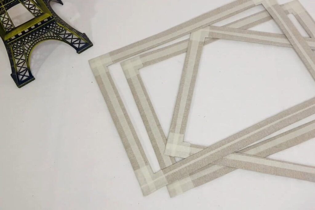 Three cardboard frame rings wrapped in masking tape stacked on a white table