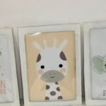 Three white DIY cardboard picture frames for nursery room wall decor, each holding a printed baby animal picture