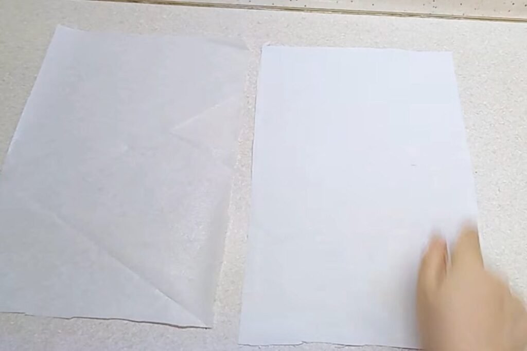 Two pieces of white material lying side by side on a table, the interfacing on the left and the base fabric on the right