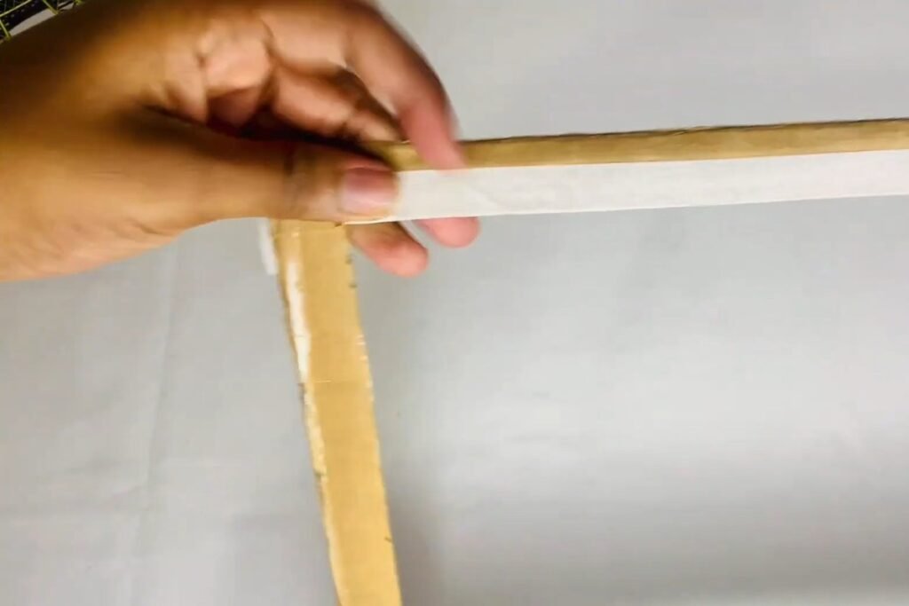 Hands holding a cardboard frame ring while masking tape is wrapped around one side