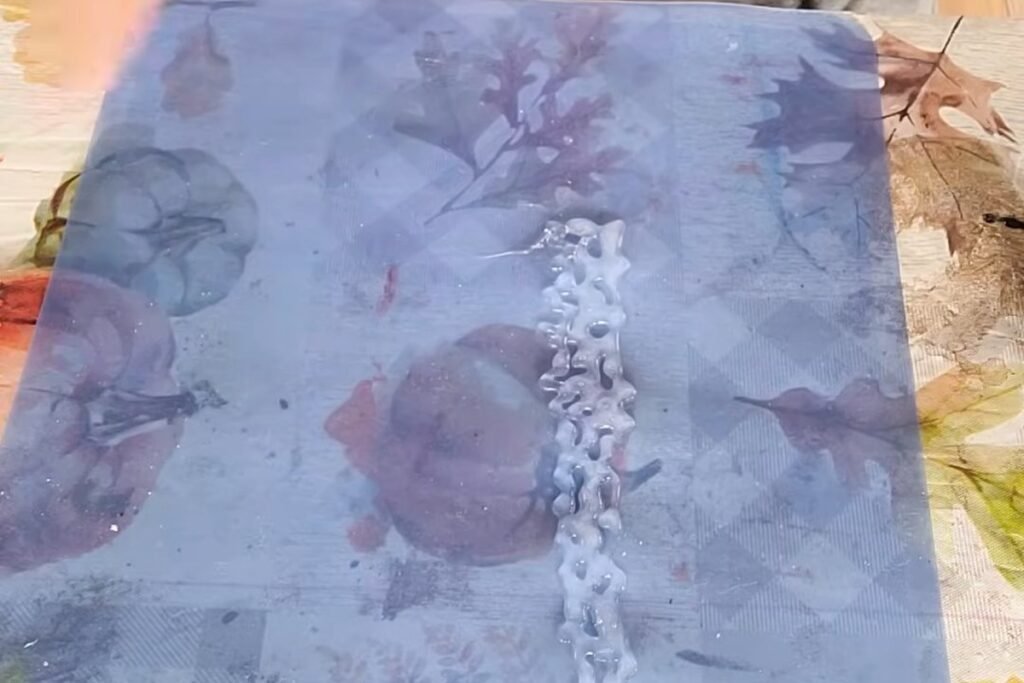 A wide lacy strip of clear hot glue lying on a smooth mat